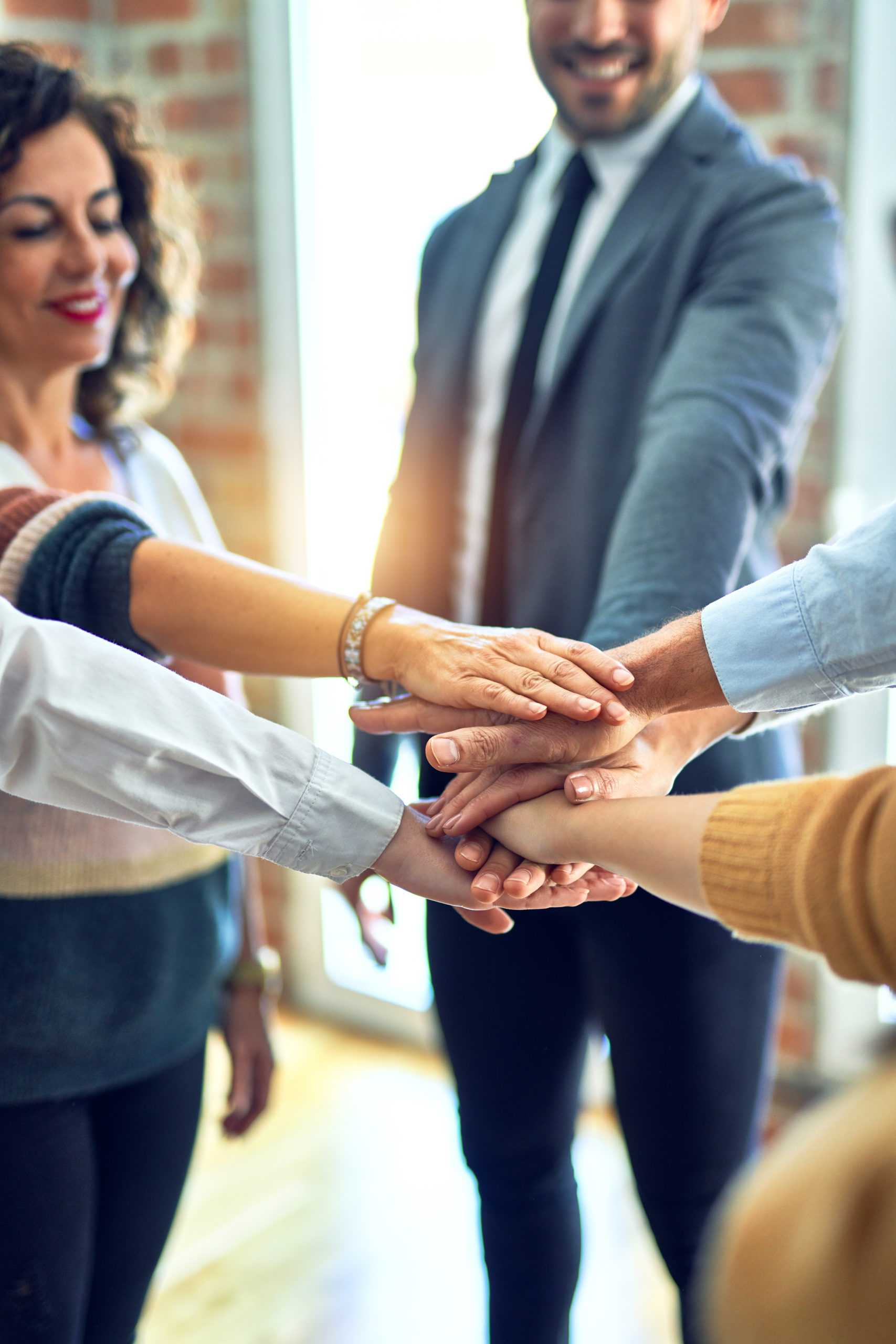 Group,Of,Business,Workers,Standing,With,Hands,Together,At,The